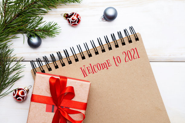 欢迎来到2021年。一张螺旋形的空笔记本的照片，棕色的床单，新年礼物，圣诞装饰品。选择性聚焦，平铺图片下载
