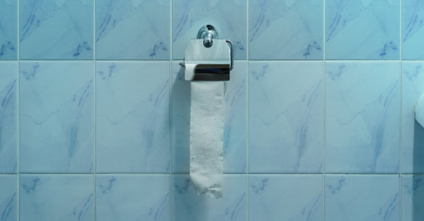 一卷撕下的卫生纸挂在酒店浴室的蓝色瓷砖墙上图片下载