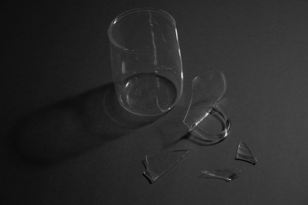 碎玻璃杯，碎片散落，孤立在黑色背景。图片下载
