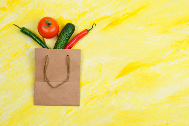 黄色背景的手工纸袋蔬菜。生态购物和食品配送理念。一个正确的营养传递的概念。平的。copyspace图片下载