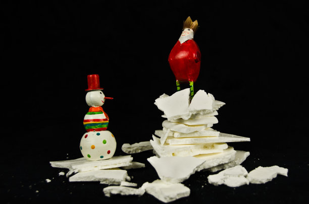 两个小的金属圣诞装饰人物，一个国王和一个雪人，国王站在一堆白雪皑皑的糖霜上图片下载