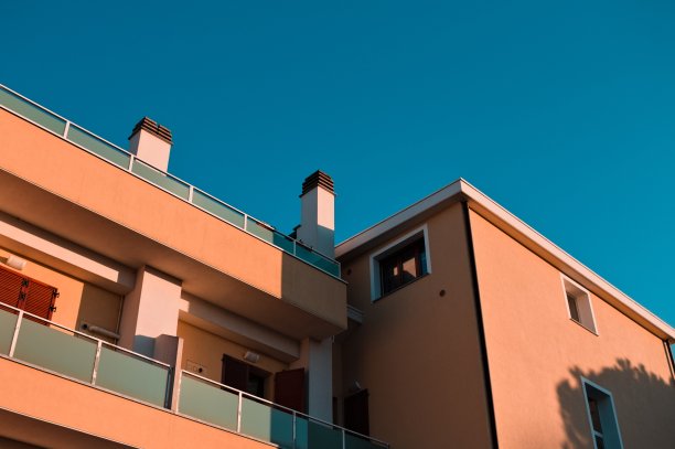 一个黄色建筑的细节，白色的烟囱和蓝色的天空背景(Pesaro, Marche，意大利)图片下载