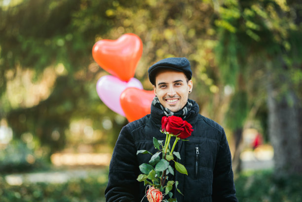 年轻男子准备约会/惊喜与玫瑰花束和心形气球股票照片。情人节的概念。求婚/订婚照片。图片下载