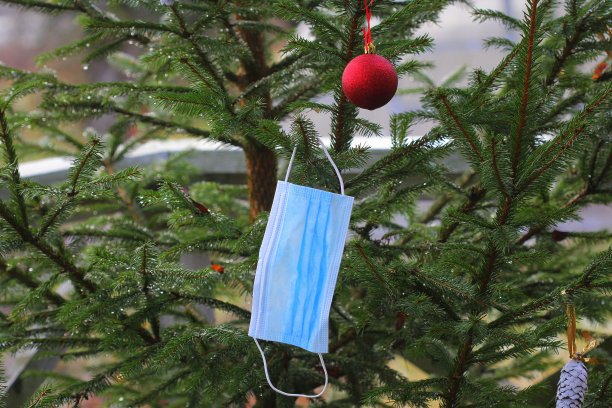 一个一次性医用口罩挂在冷杉树枝上作为圣诞装饰，是疫情期间的礼物。圣诞树在新的一年里的实际装饰图片下载