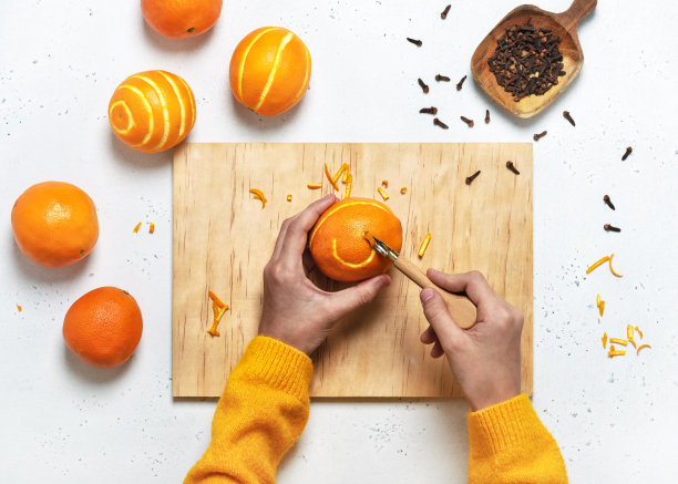 俯视图的女孩的手雕刻成一个橙子的圣诞装饰。图片下载