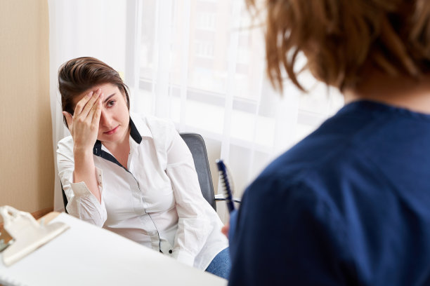 医生正在和年轻的女病人交谈，并站在旁边做笔记图片下载