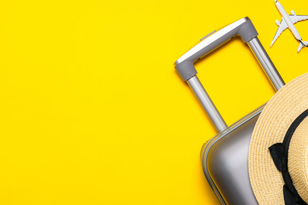 夏天背景表。手提箱、棕叶太阳镜、草帽、黄色背景上白色飞机的旅行构图。复制空间，暑假和商务旅行的概念。图片下载
