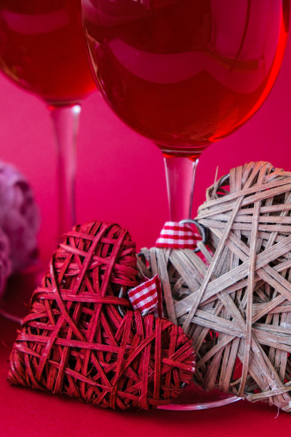 两杯红酒和装饰心。爱浪漫。夫妇关系。红色哑光背景。白色和红色元素。情人节浪漫晚餐图片下载