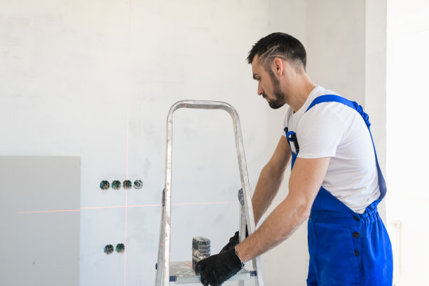 穿工作服的建筑工把梯子移到墙上图片下载