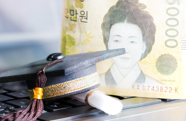 E-learning在线研究生教育理念:毕业帽，证书学位笔记本电脑模糊外币韩币钞票背景。在线学习可以通过网络进行远程学习，提高学习效果图片下载