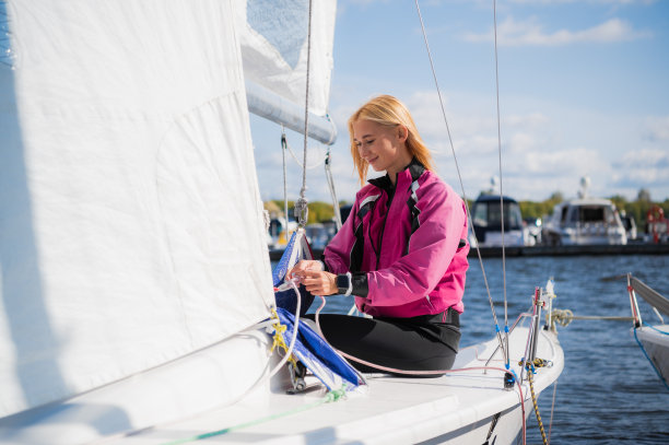 年轻的运动女孩在船坞的游艇上穿着运动服准备参加帆船赛图片下载