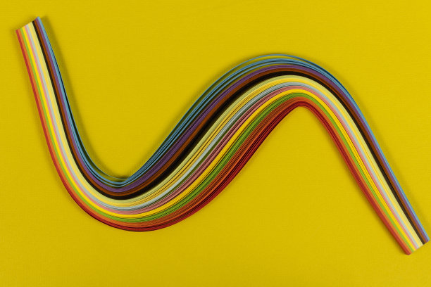 黄色背景上的彩色羽毛纸。抽象的背景纹理。图片下载