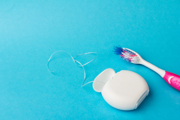 蓝色背景上的牙线和牙刷。个人牙科卫生用品。图片下载