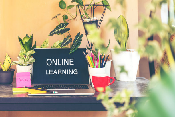 学习在线文字在笔记本电脑屏幕上的桌子上，植物和咖啡杯在家里的自然花园。技术与教育理念图片下载