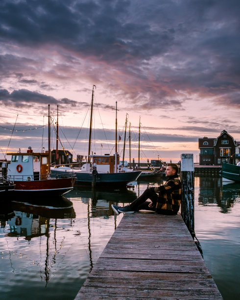 荷兰厄克弗莱弗兰，一对男女在荷兰厄克的小渔村港口观看日落图片下载