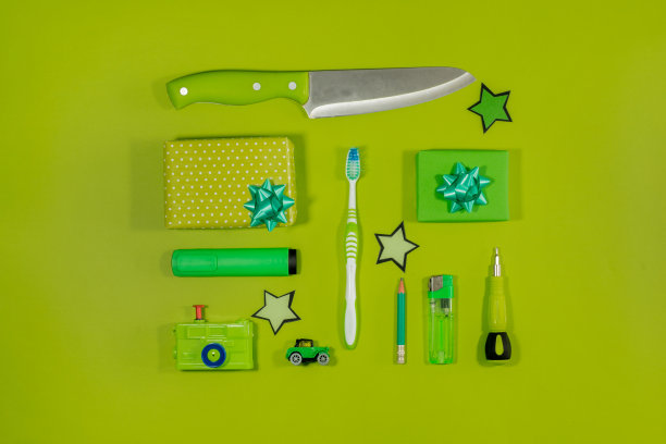 绿色物品平铺：刀片、螺丝刀、牙刷、打火机、礼物、荧光笔、塑料车、塑料相机、铅笔图片下载