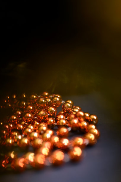 橙色的珠子和圆形的珠子装饰圣诞树，特写在一个黑暗的背景。图片下载