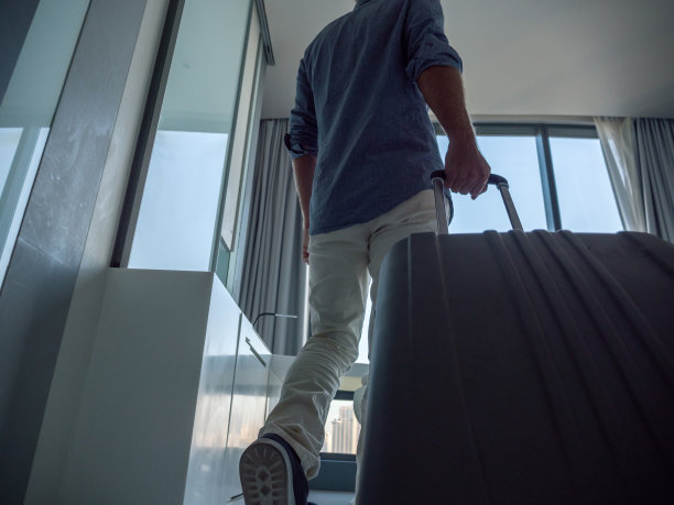 一名男子带着随身行李进入酒店房间图片下载