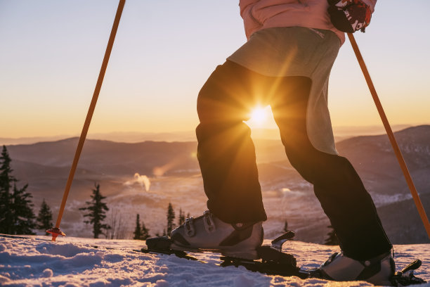 日落时分，滑雪女选手站在山顶的剪影，美丽的冬季山景图片下载