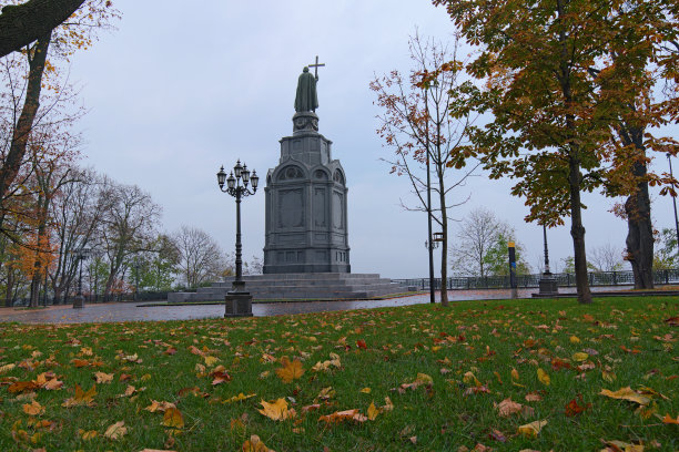 低角度的宏伟的秋天彩色Volodymyr山(Vladimirskaya Girka)。橙色的落叶落在绿色的草地上。著名的伏尔基米尔大帝纪念碑周围是秋天的彩色树木图片下载