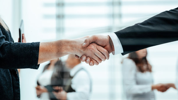 通过百叶窗。商务人士的握手。商业背景图片下载