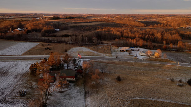 鸟瞰图美国中西部乡村景观在春季和冬季。农田被雪覆盖，农舍被雪覆盖。阳光明媚,日落图片下载