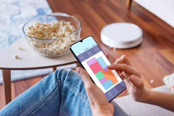 一个女人在她的智能手机上使用机器人吸尘器应用程序的特写镜头图片下载