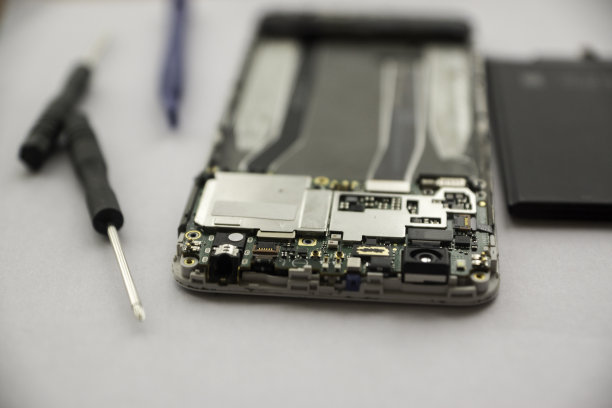 关于智能手机维修的概念。拆下来的手机小玩意放在桌上，周围有螺丝刀工具，零配件。选择性聚焦，浅景深图片下载