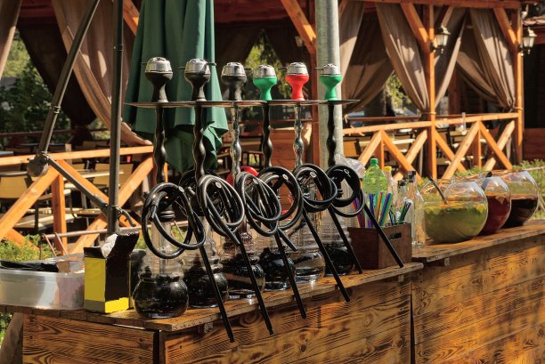 在一家开放的夏季餐厅里，棕色的木桌上放着一排黑色水烟图片下载