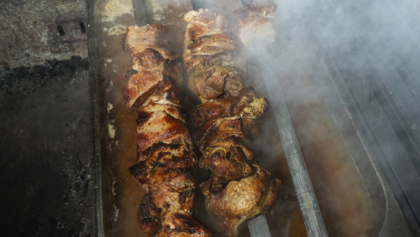 深色背景上，串在烤肉串上烤的烤肉串。前景上散焦的烟雾。街头食品的概念。图片下载