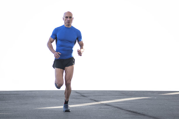 在一个阳光明媚的日子里，一个运动员穿着运动服在马路上跑步。体育的概念图片下载