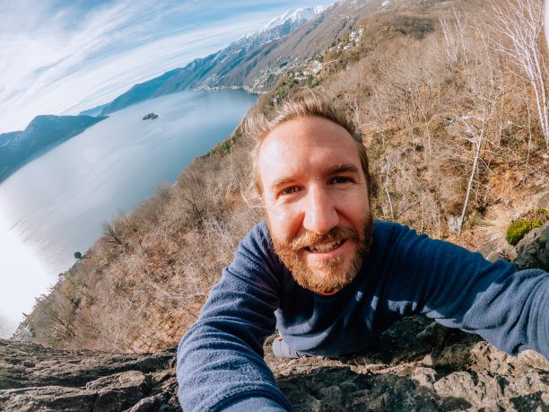 一名登山者在岩壁上方自拍图片下载