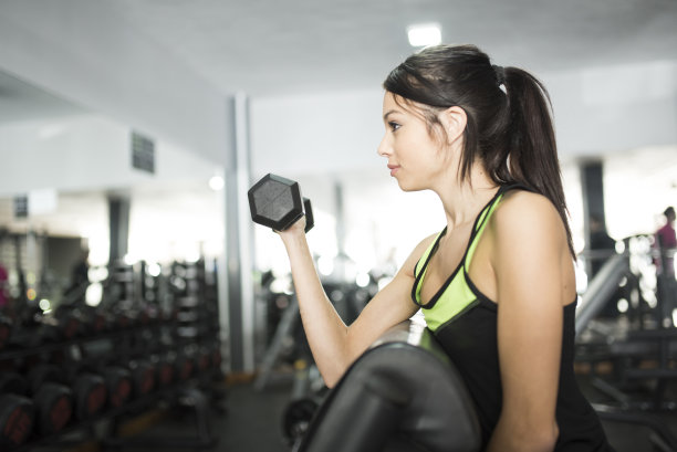 女人一边锻炼二头肌一边看着镜子里的自己图片下载