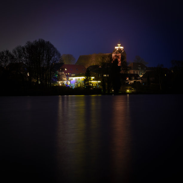 教堂的圣诞彩灯在黑暗中倒映在湖面上图片下载