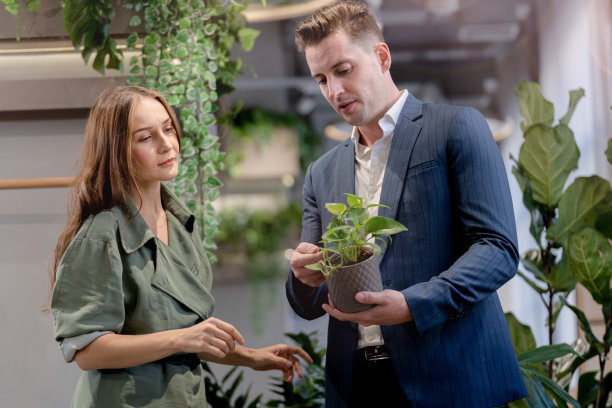 快乐的商人和女人的肖像在室内建筑花园的盆栽绿树植物叶子。亲生命的自然概念办公空间。图片下载