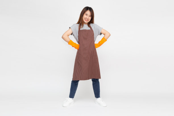 年轻的亚洲妇女的肖像站着，戴着橙色橡胶手套的手保护清洁隔离在白色的背景图片下载