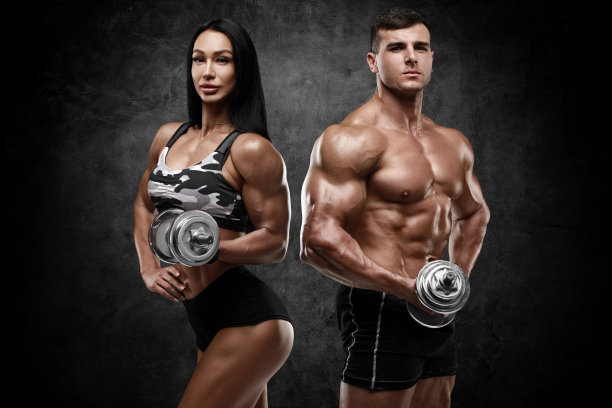 运动夫妇在墙上用哑铃做背景。肌肉发达的男人和女人图片下载