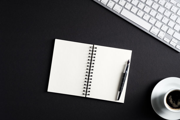 黑色的办公桌桌上有空白纸记事本，钢笔，电脑键盘，咖啡杯。顶视图与复制空间，平放。优雅的工作区。经营理念。图片下载