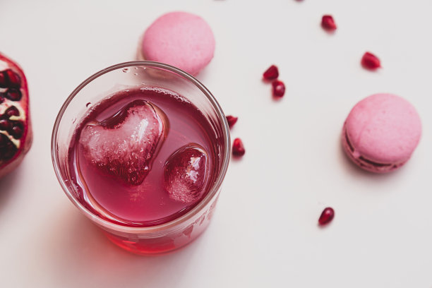 极简主义的静物生活与石榴水果和石榴汁在一个玻璃玻璃与一个心的形状的冰块在一个光线背景选择焦点图片下载