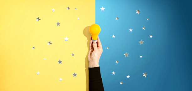 一个人拿着一个带星星的黄色灯泡图片下载