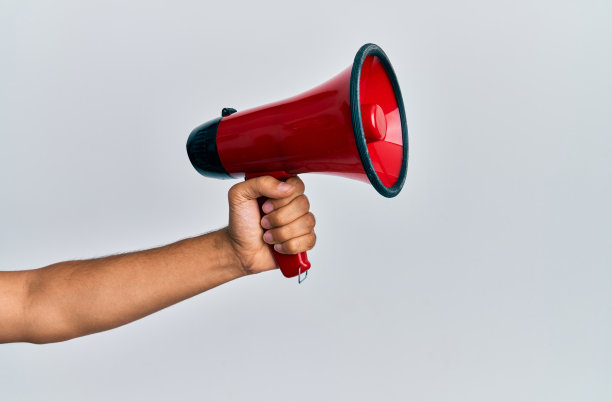 西班牙裔男子手持扩音器，背景是孤立的白人。图片下载