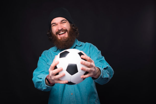 我们去踢足球吧。快乐的大胡子男人拿着足球，看着镜头图片下载