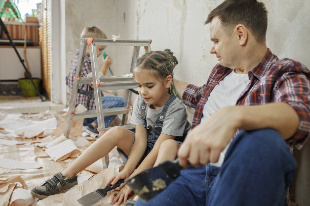 父亲和孩子一起修补房间，一起拆墙纸图片下载