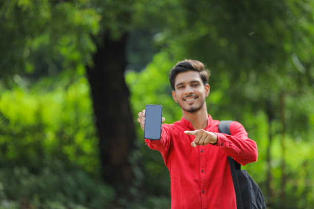 年轻的印度大学生在自然背景下展示智能手机图片下载