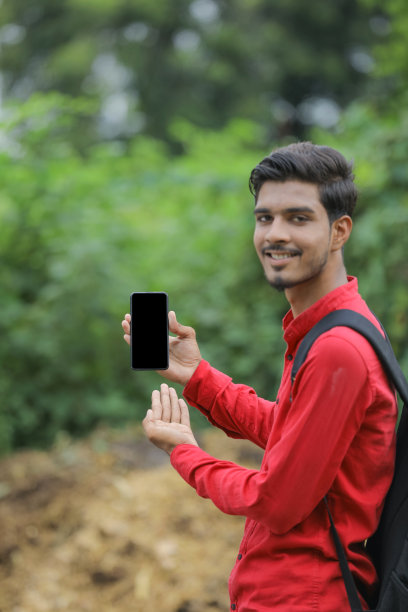 年轻的印度大学生在自然背景下展示智能手机图片下载