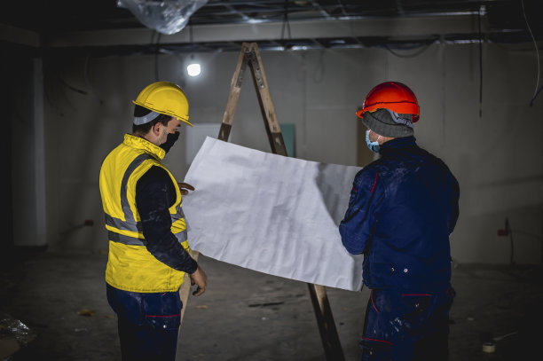 两个戴面罩的建筑工人在检查蓝图图片下载