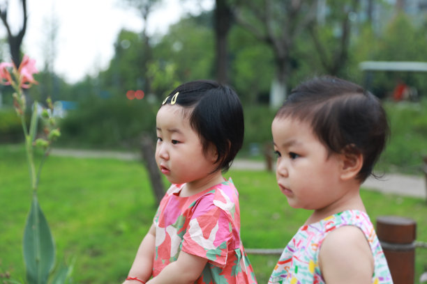 这是公园里两个穿着五颜六色衣服的中国小女孩的侧面照片图片下载