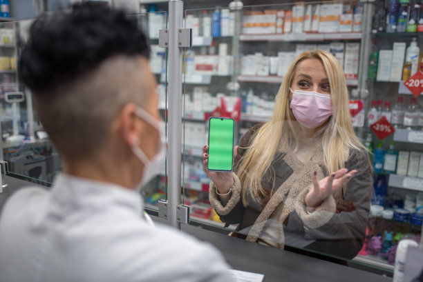 顾客正在向药剂师展示电话屏幕图片下载