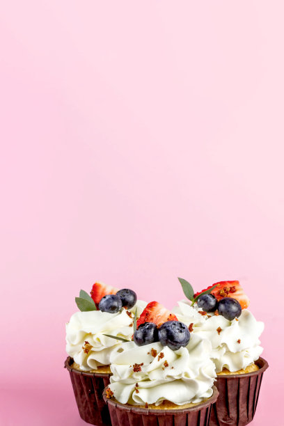 美味的纸杯蛋糕与奶油和新鲜的浆果孤立在粉红色的背景。副本的空间。图片下载