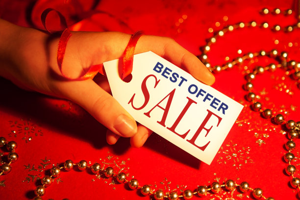 一位女士手里拿着一张标签，上面写着:圣诞节和新年假期期间，有装饰的圣诞背景，最优惠销售。图片下载